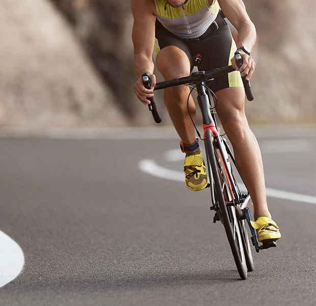 Cycliste en tenue de sport sur un vélo de route, en plein virage.